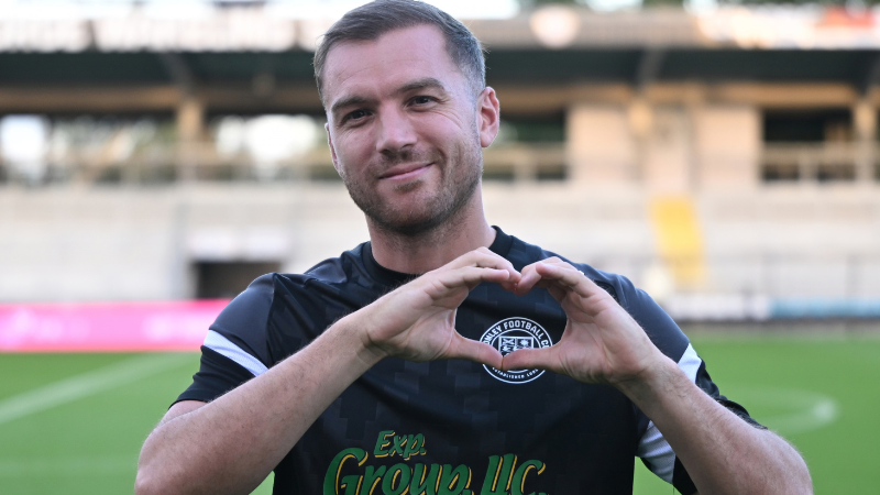 Photo of Michael Cheek, Striker for Bromley FC making heart sign with his hands while wearing a Bromley FC kit.