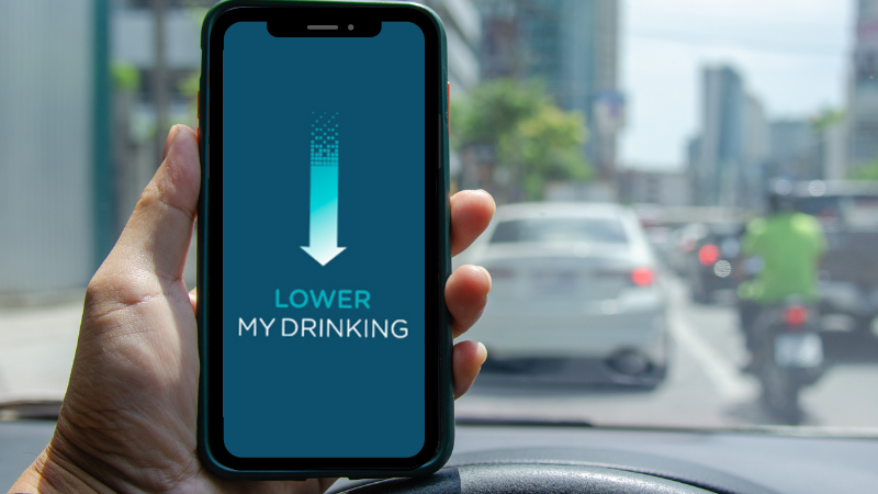 Image shows a person holding a phone up displaying the words Lower my drinking with a downward arrow