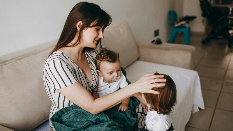 Photo showing a parent sat with two children in a living room.