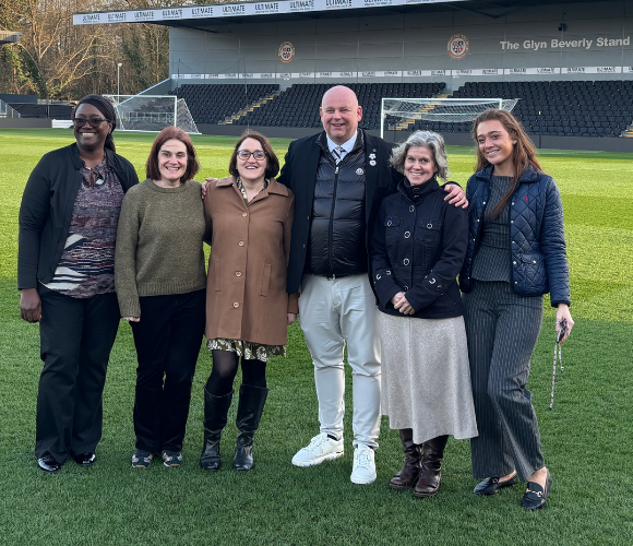 Photo of two Bromley FC representatives with members of Bromley’s Public Health team on the pitch at the CopperJax Community Stadium.