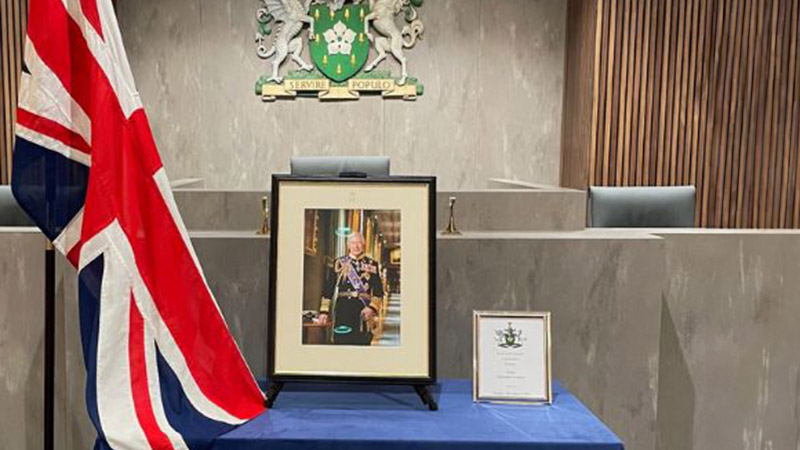 Portrait of King Charles Third with the Union Jack flag on the left.