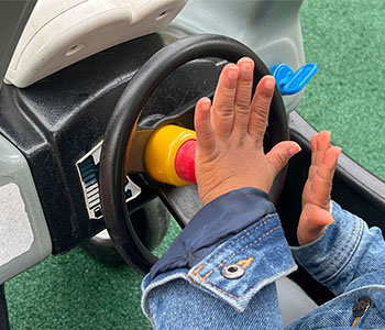 Child’s hand in a toy car pressing the horn.