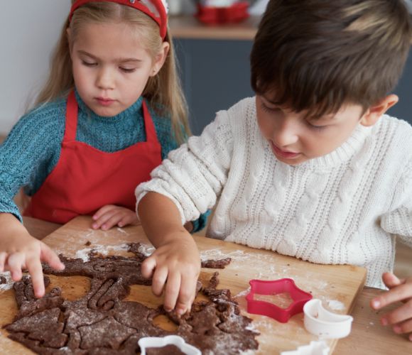2 children making cookies using cookies cutters.