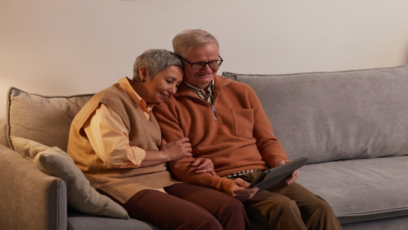 Couple sitting on a sofa with a laptop.