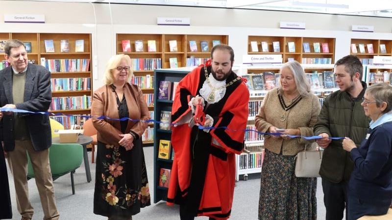 Mayor cutting the ribbon inside Mottingham Library at reopening.