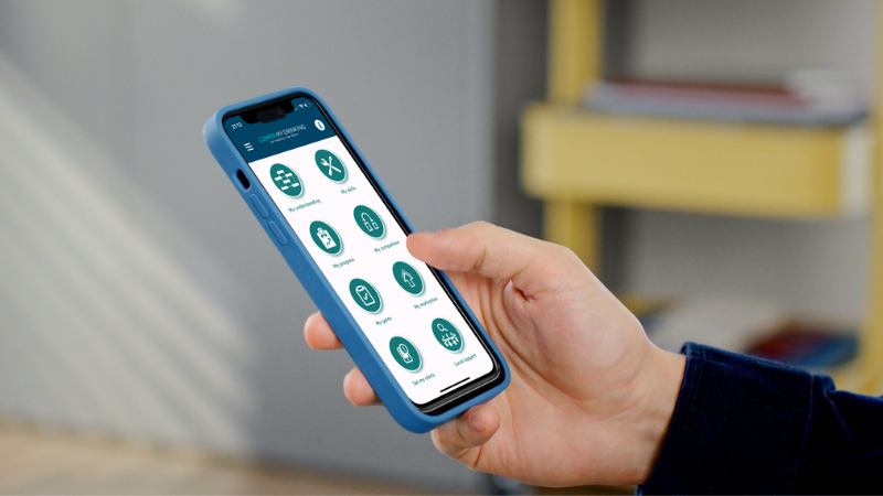 Photo of a hand holding a smartphone displaying the Lower My Drinking App's homepage.