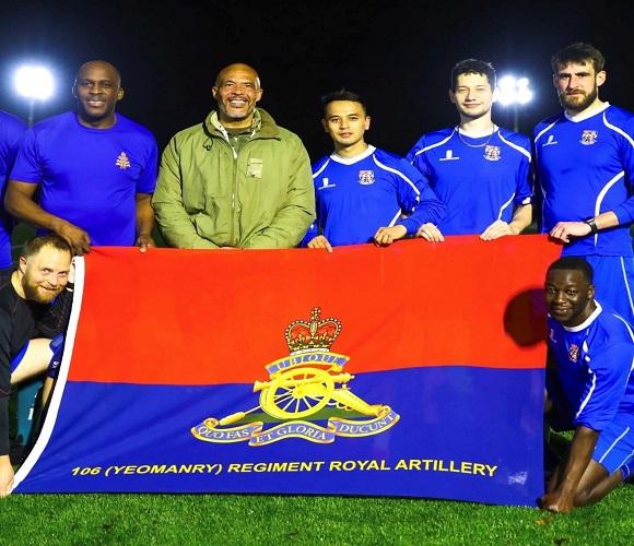 Players on the pitch with a 106 Yeomanry Regiment Royal Artillery flag.
