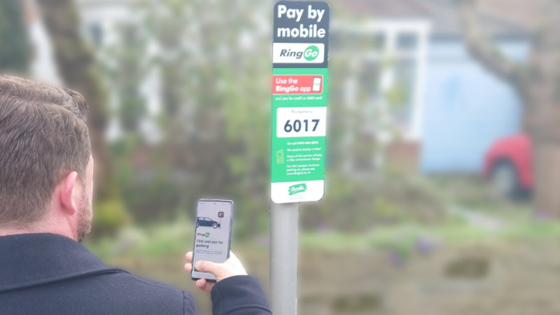Picture shows a man using a mobile phone to pay for a parking session.