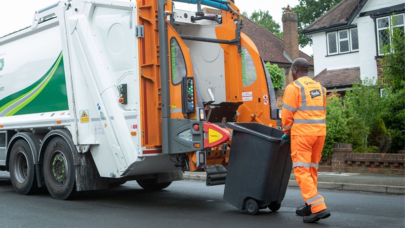 Waste truck and worker with a wheelie bin.