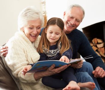 Experienced foster carer couple having a happy moment with a young girl whilst reading a book.