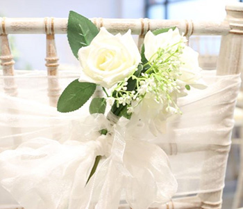 Chiffon Bow draped on a chair with an artificial rose.