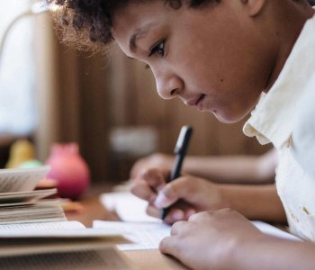 Image shows a child sitting at a desk writing.