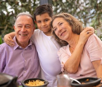 Old age foster care couple with a young boy in care having lunch in the garden.
