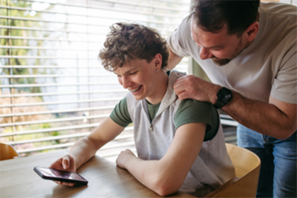 A foster carer and teenager sitting together at a table, with the carer supporting the teenager.