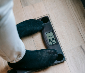Photo of person’s feet while standing on weight scales with a reading displayed on the screen.