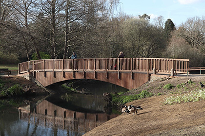 Kelsey Park new footbridge over a stream with pedestrians.