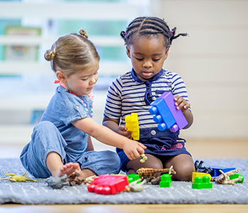 Two young children playing together with toys in an early years setting.