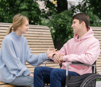 A young woman talking with a young man in a wheelchair.