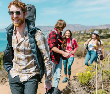 Group of friends hiking outdoors on a sunny day near the coast.