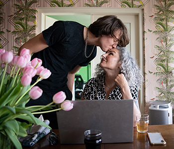 A young boy who is representing a young carer for a female adult supporting her within the home environment.